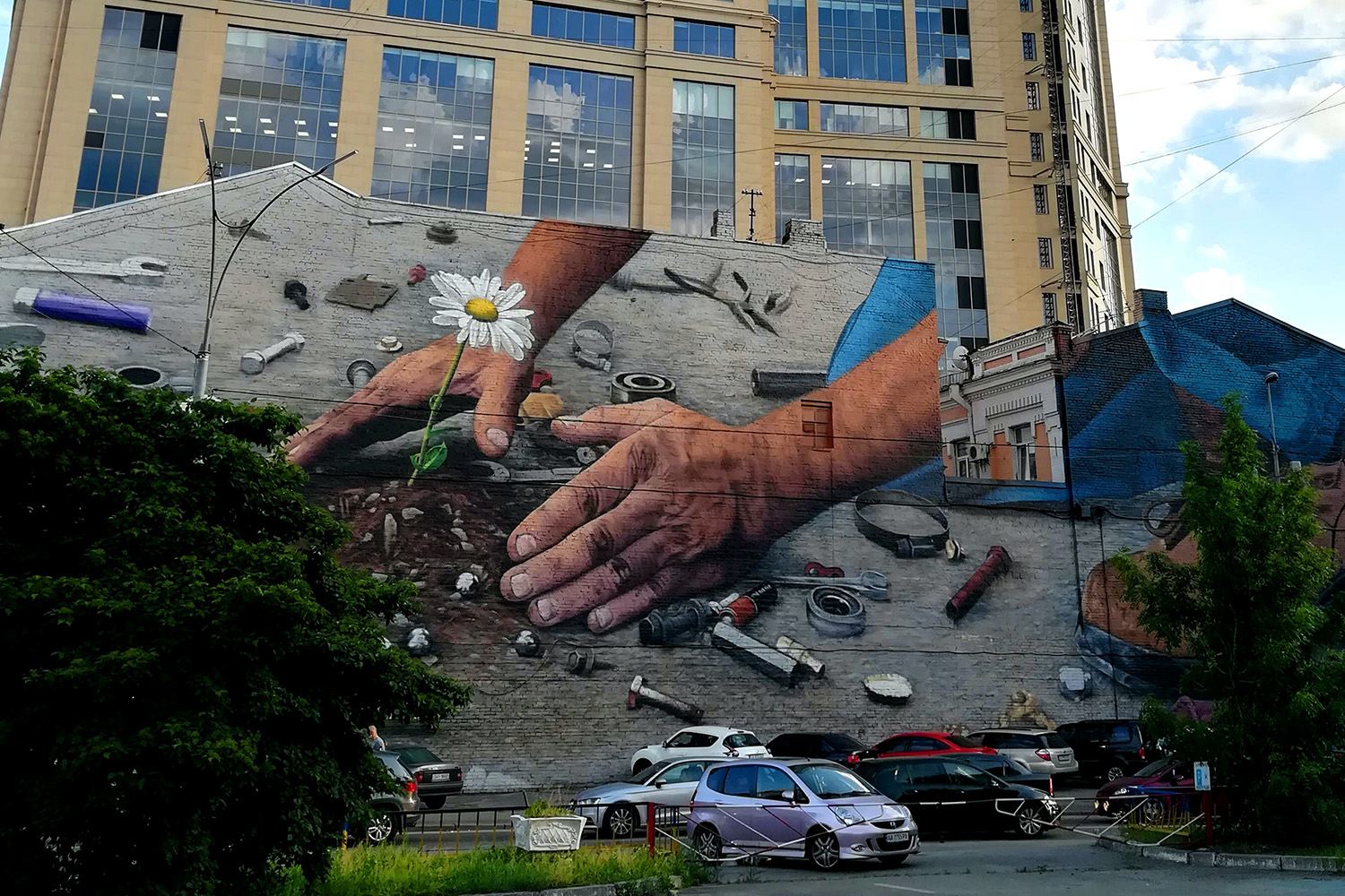 Mural painting in Kyiv of two hands planting a flower in cracked asphalt.